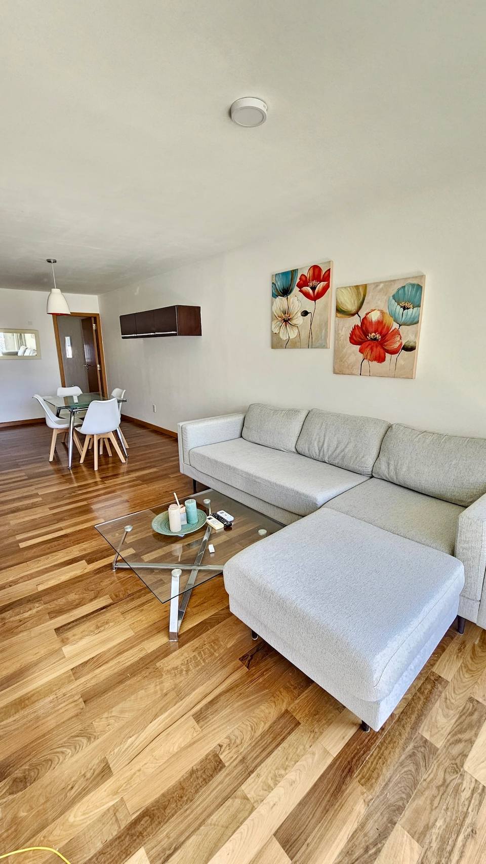 Sala com sofá e quadros, zona de refeições ao fundo