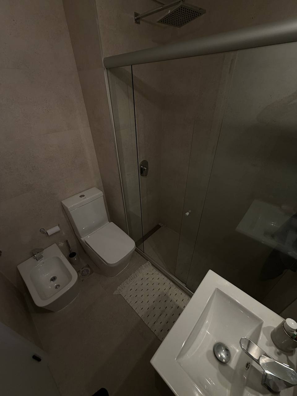 Toilet, bidet, sink, and shower with screen.