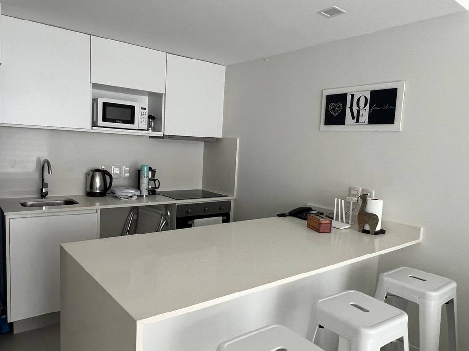 Cocina con mesada blanca y taburetes