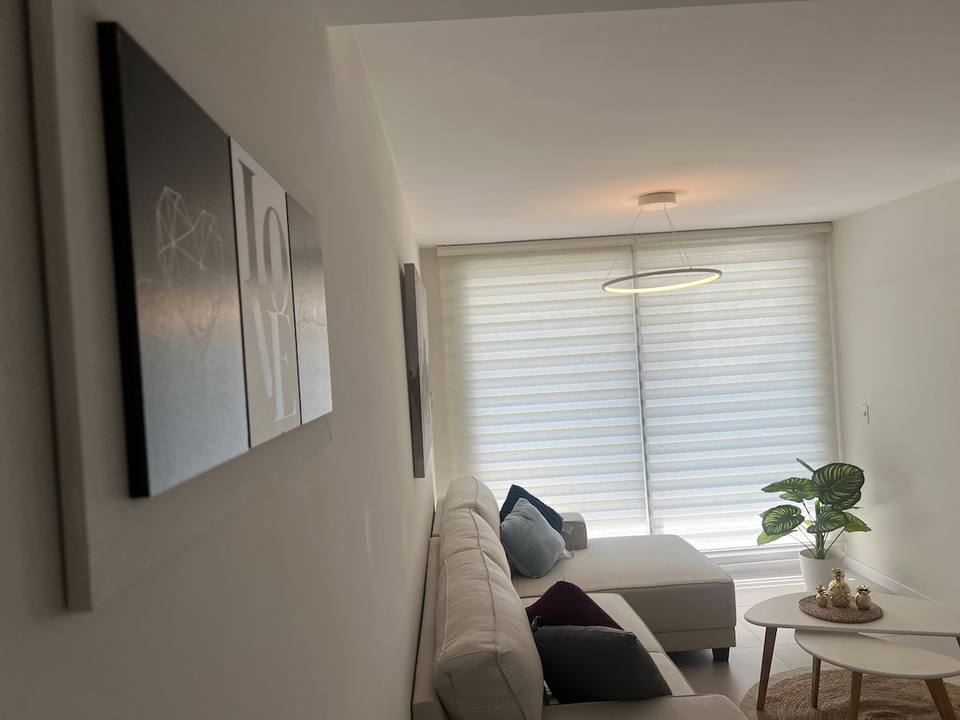 Sala con sofá, ventanas y cuadros.