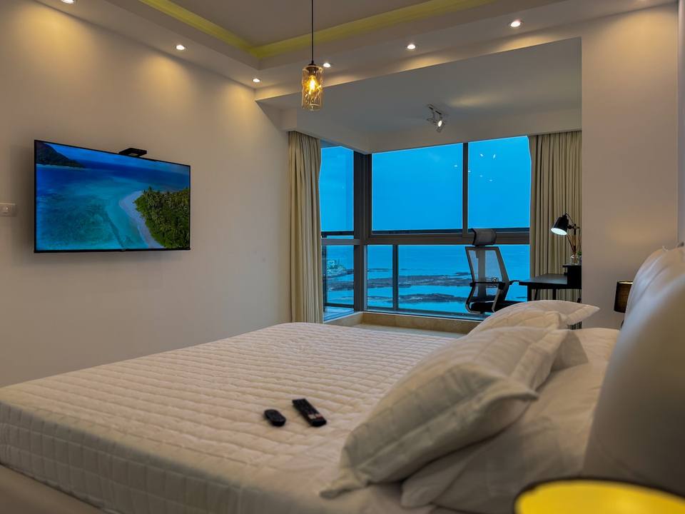 Dormitorio con cama, escritorio, televisión y vistas.