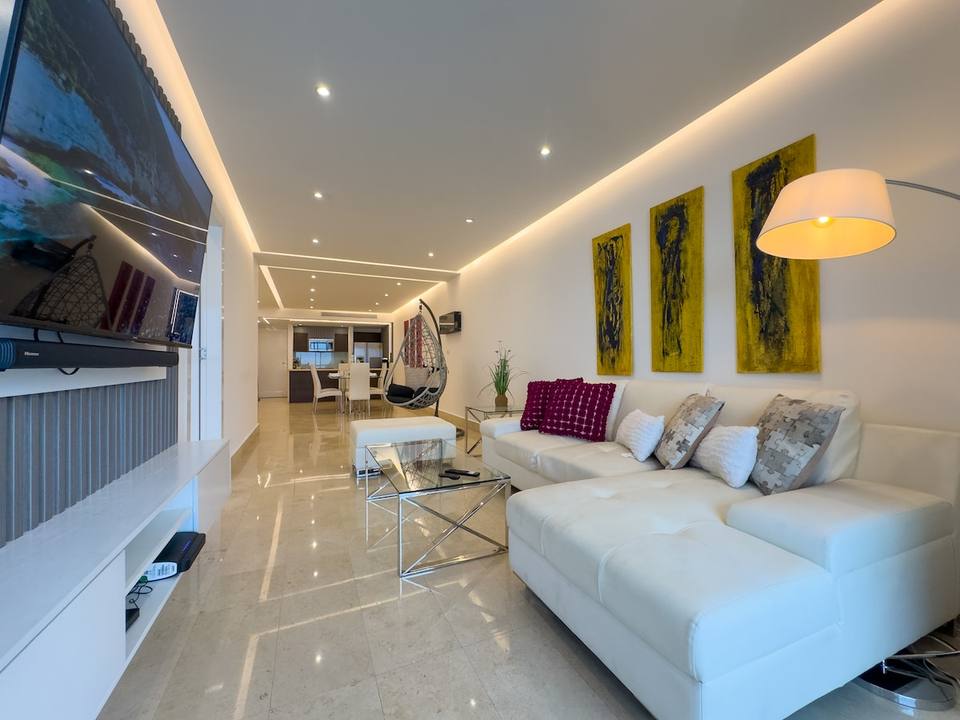 Sala con sofá blanco, televisor grande