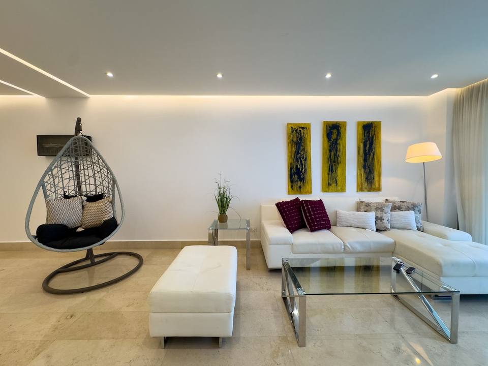 Sofá blanco, arte abstracto, silla colgante, lámpara de pie.