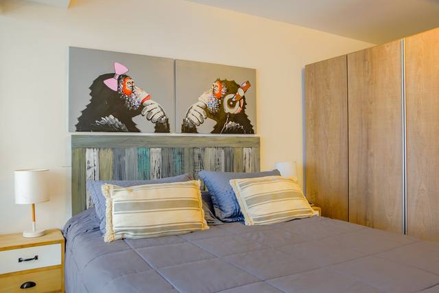 Cama doble con cabecero y obras de arte