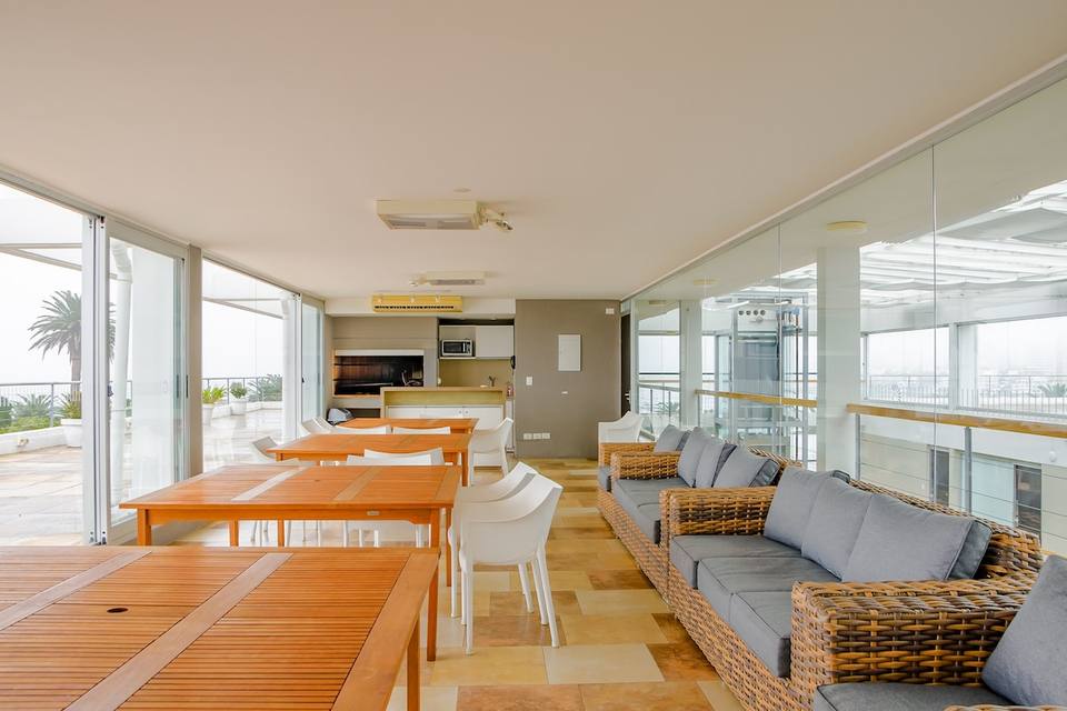Espacio social interior con parrilla, mesas y sofás