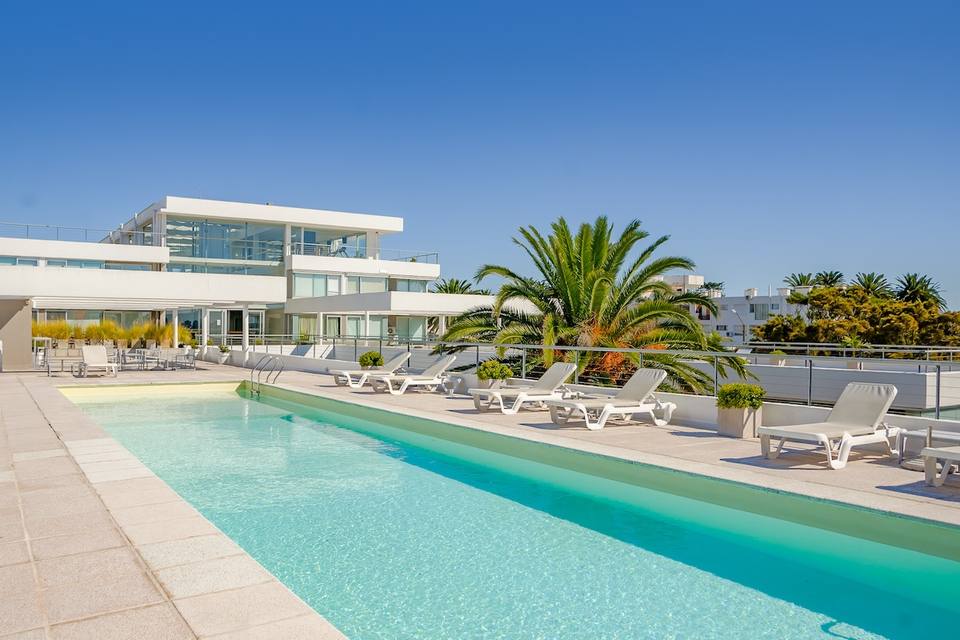 Piscina exterior con tumbonas y edificio moderno
